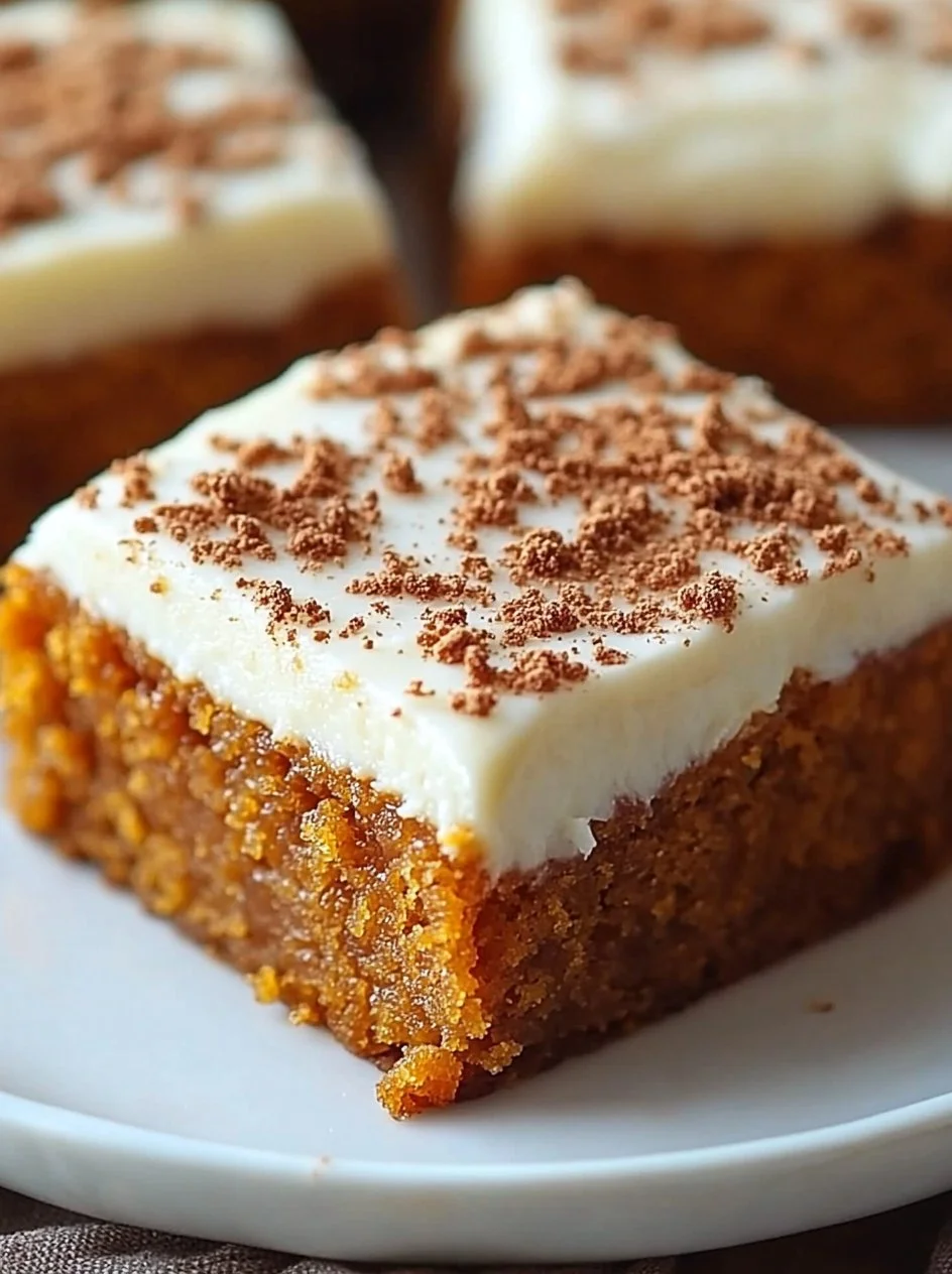 Pumpkin Bars with Cream Cheese Frosting 2 Pumpkin bars topped with cream cheese frosting on a plate