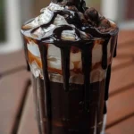 Delicious black milkshake in a tall glass with whipped cream and chocolate drizzle